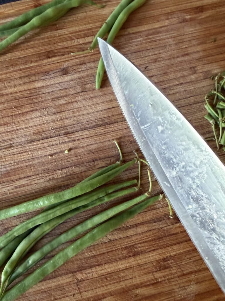 Topping green beans with a chef's knife