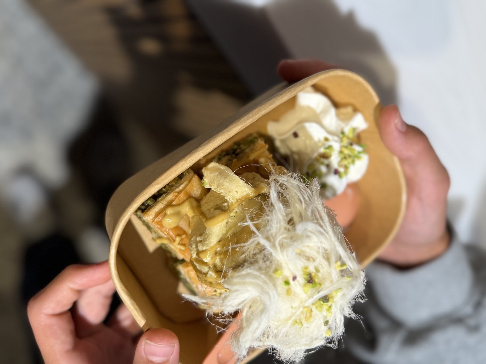 Candy floss and pistachio on a spoon over baklava and ice cream