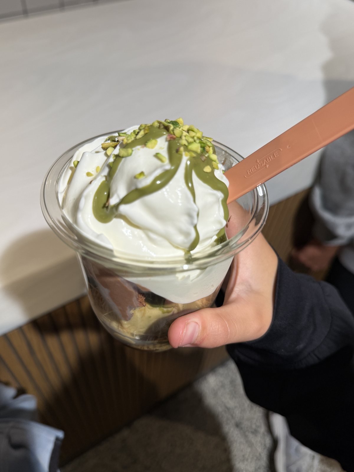 Layered cup with cream, pistachio sauce and chocolate at Miska